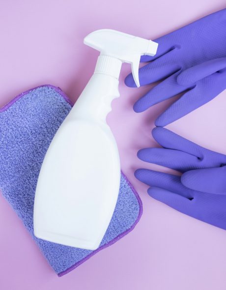 Cleaning concept. Rubber gloves, house-cleaning spray and sponge on pink background